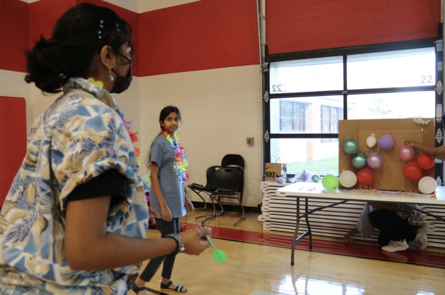 CHS9 student Sandhya Karthick gets ready to throw a dart at balloons during the Sadie Hawkins dance on Friday in the gym on campus. The dance’s theme was “Family Vacation” and was organized by the CHS9 Student Council.
