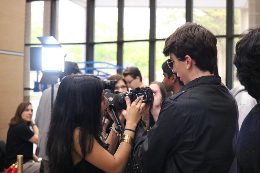 Coppell High School juniors Swarra Mudgalkar and Bunker Harris set up camera equipment to interview KCBY-TV seniors on the red carpet. The KCBY-TV Film Fest was held on March 31 and transformed the CHS Vestibule and Auditorium into a Hollywood venue to showcase student filmmaking in Coppell. 