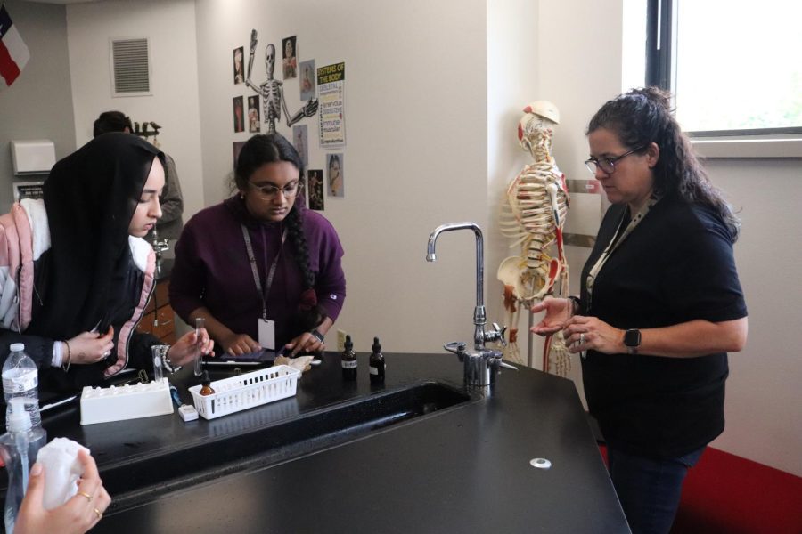 Coppell High School Honors Anatomy & Physiology teacher Jodie Deinhammer assists juniors Harini Hariharan and Nazia Quadri with their standard synthetic urinalysis lab in third period on Monday. Deinhammer was selected as The Sidekick’s Volume 34 Issue 6 Teacher of the Issue.