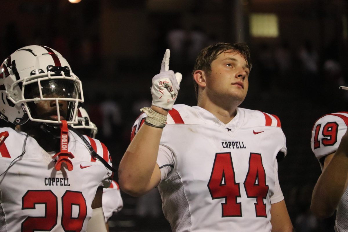 Coppell junior defensive end Blake Isbel and senior running back Xavier Mosley signal “guns up” while singing Coppell’s alma mater after the game against South Grand Prairie at Gopher-Warrior Bowl on Friday. Coppell defeated the Warriors, 44-34.