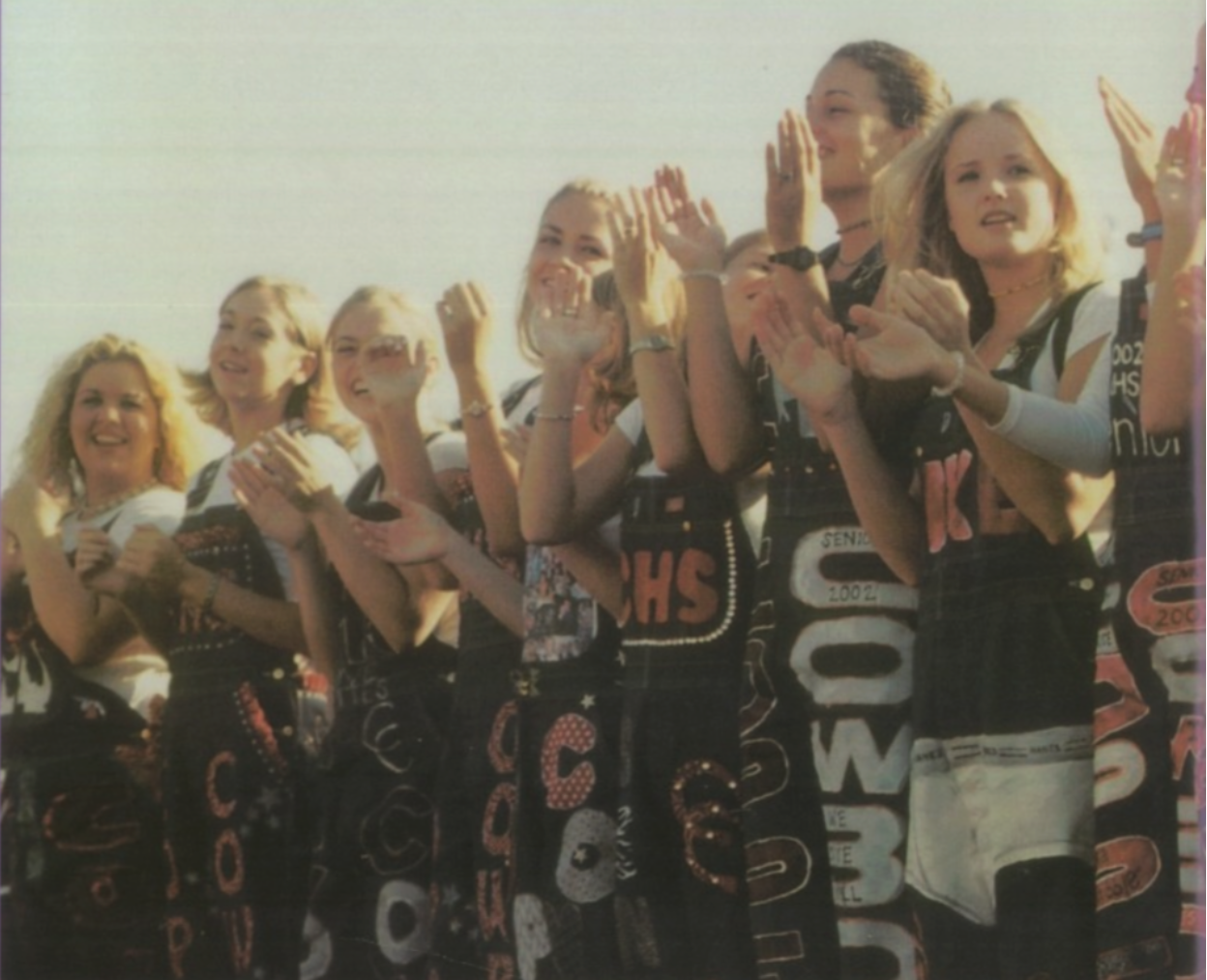 Coppell High School class of 2002  wear their senior overalls in the student section at a pep rally. Senior overalls have been a tradition since the early 2000s as a way for senior girls to represent their school spirit and pride in Coppell. 