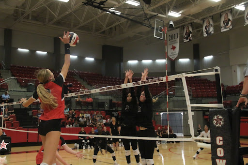 Coppell senior setter/opposite hitter Mira Klem spikes the volleyball over Lewisville blockers after receiving a set from middle blocker Katie Keith. The Cowgirls  won 25-16, 25-10, 25-15 against the Farmers on Wednesday Sept. 13.
