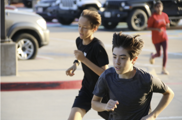 Coppell freshman cross country runners Lucas Ortigoza and Henry Hayden run through the CHS parking lot as a part of early morning practice. The Coppell cross country team has been focusing on improving their endurance and stamina as the District 6-6A Championship on Oct. 13 approaches. 