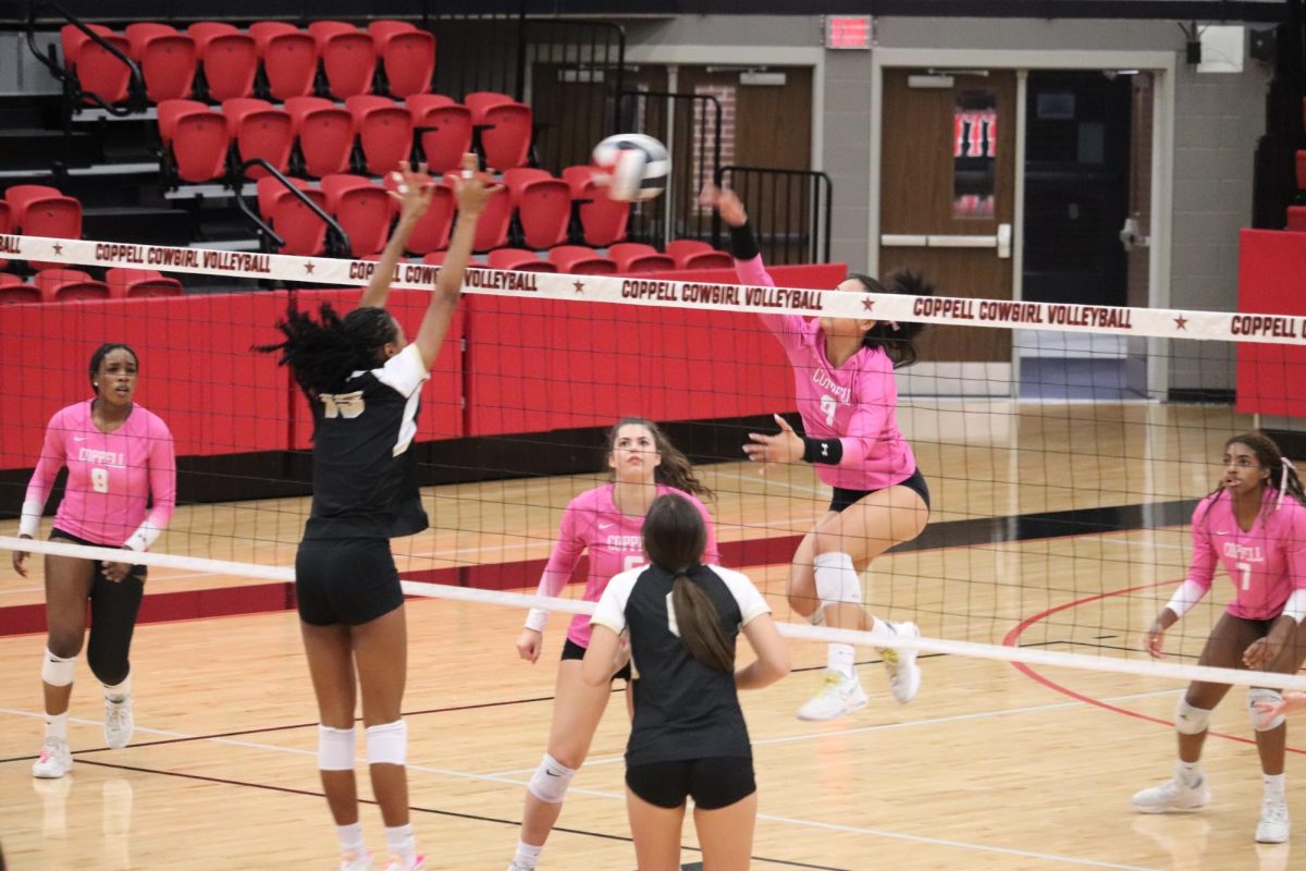 Coppell senior setter Alena Truong spikes the ball as Plano East middle hitter Summer Stephens blocks in CHS Arena on Friday. The Cowgirls lost, 26-24, 25-17, 25-22, to the Lady Panthers.