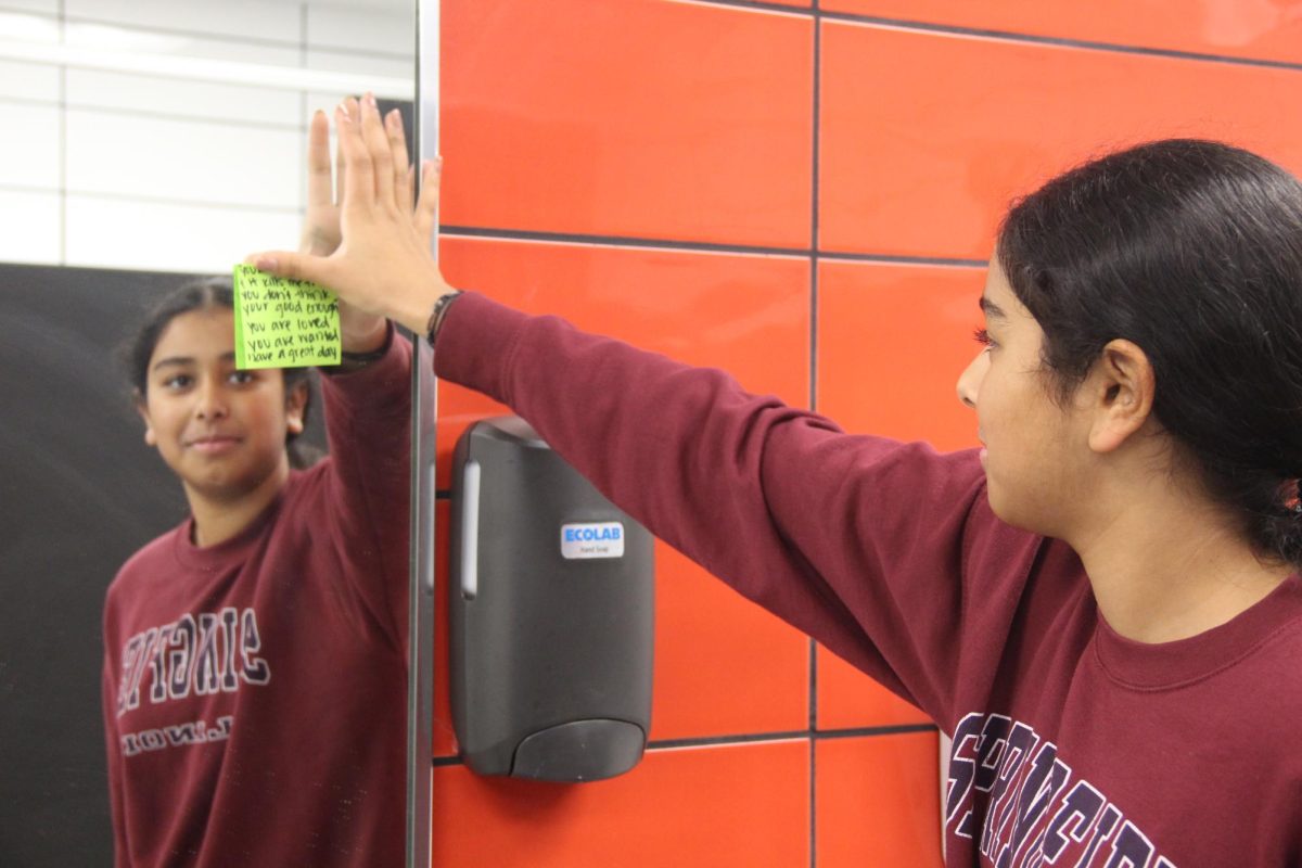 CHS9 student Varshita Nidamanuri places a sticky note with an encouraging message on the mirror in the F hall restroom. Hope Squad is a suicide prevention program to reduce youth suicide through education, training and peer intervention. Photo by Sukirtha Muthiah
