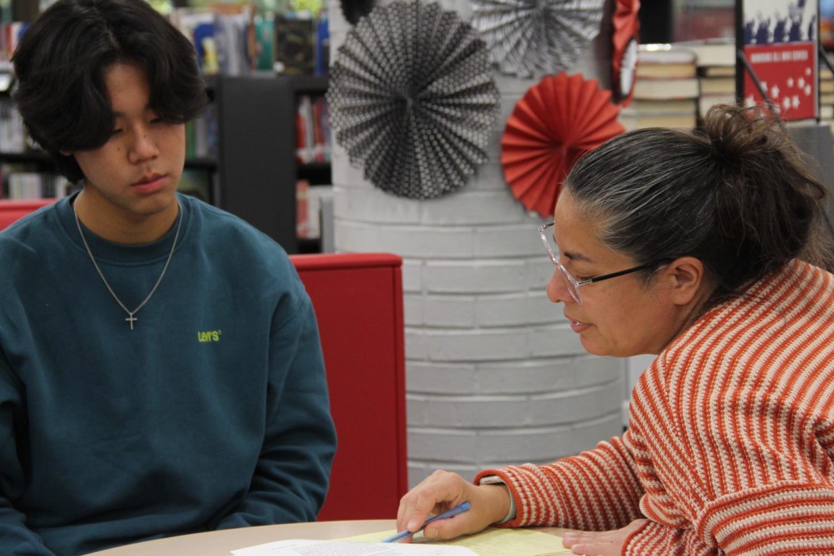 Coppell High School English Honors II teacher Ericka Cansino gives sophomore Solomon Lee feedback and corrections on his timed writing on Nov. 1 at the CHS Library. Cansino stepped into her teaching role two months into the 2023-24 school year with her unique background in education.