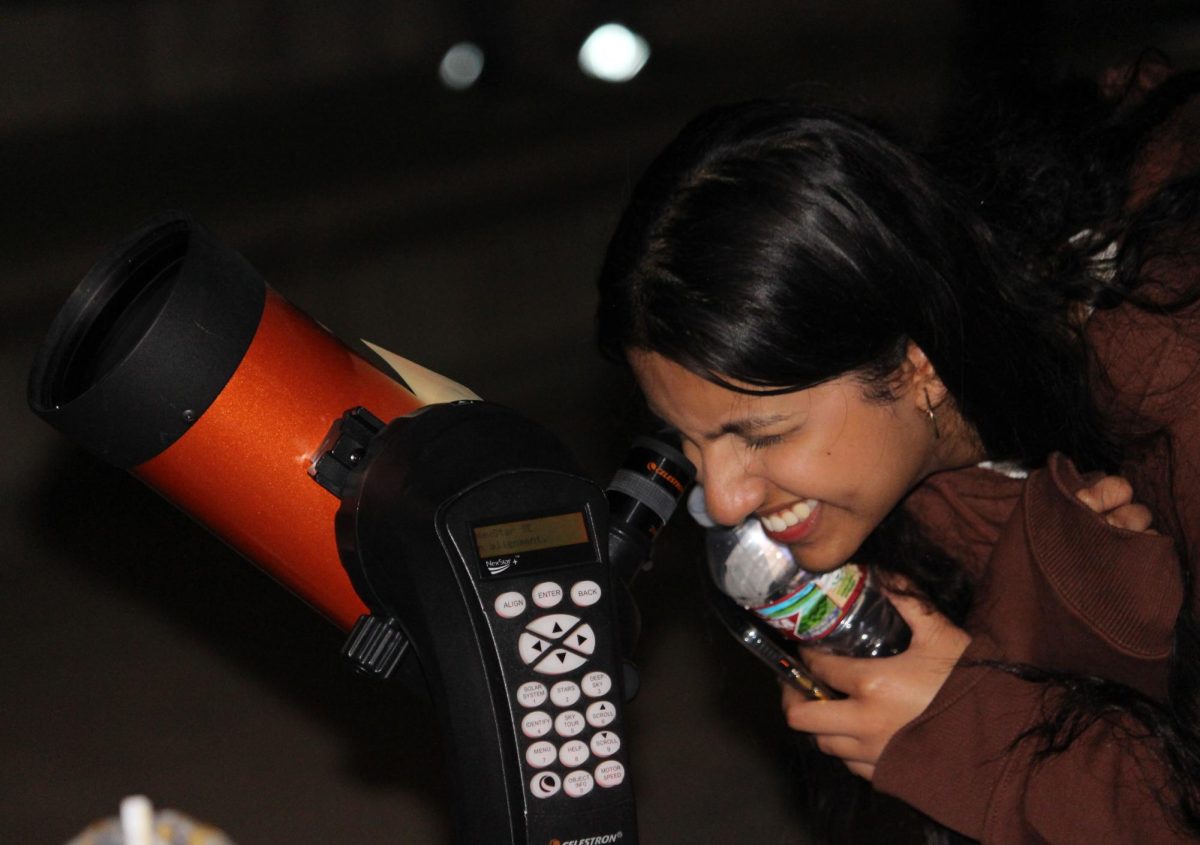 Coppell High School senior Daniya Dias views the night sky through a Celestron 4-inch telescope at the CHS main entrance. CHS Honors Astronomy’s annual Moon Party was held on Wednesday for students to showcase their knowledge and celebrate the moon with members of the community.