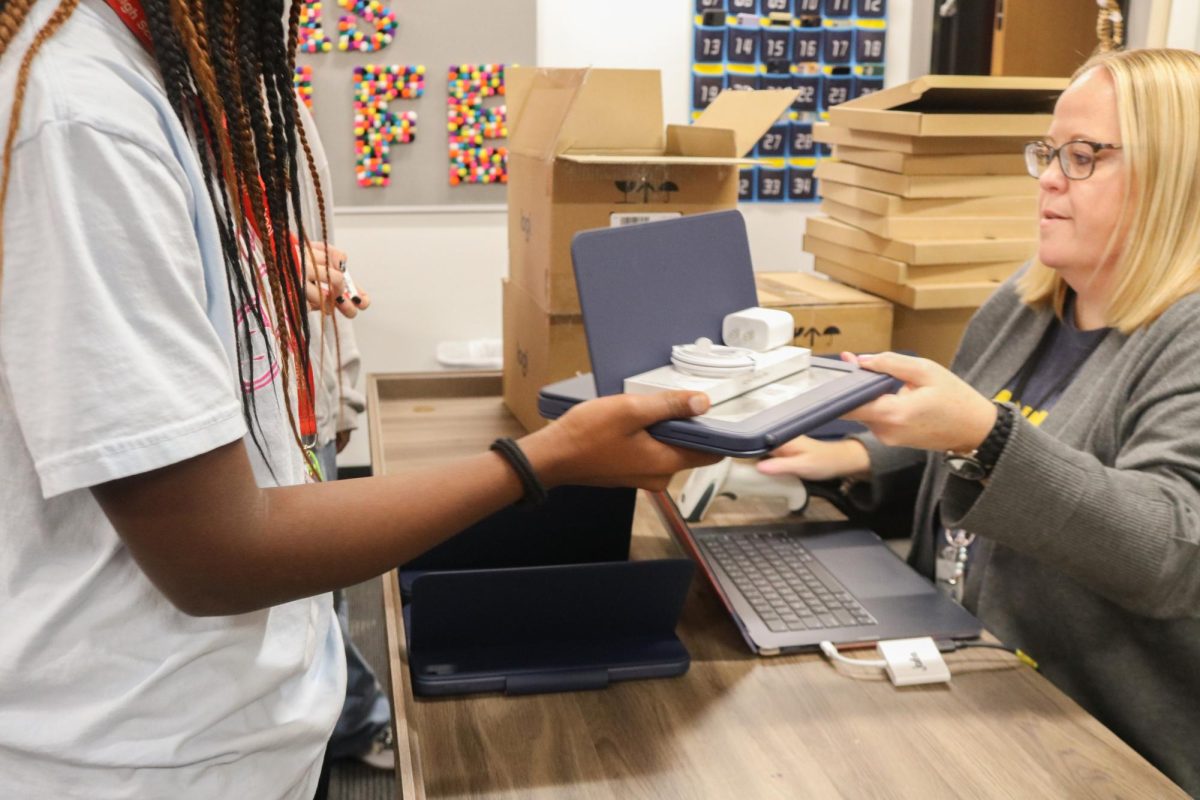 Coppell ISD digital learning coach Julie Bowles hands an iPad to junior AnneMarie Oilepo on Wednesday. Coppell ISD provided new devices and accessories to students in grades 6-11 as a part of the 2023 bond package. 

