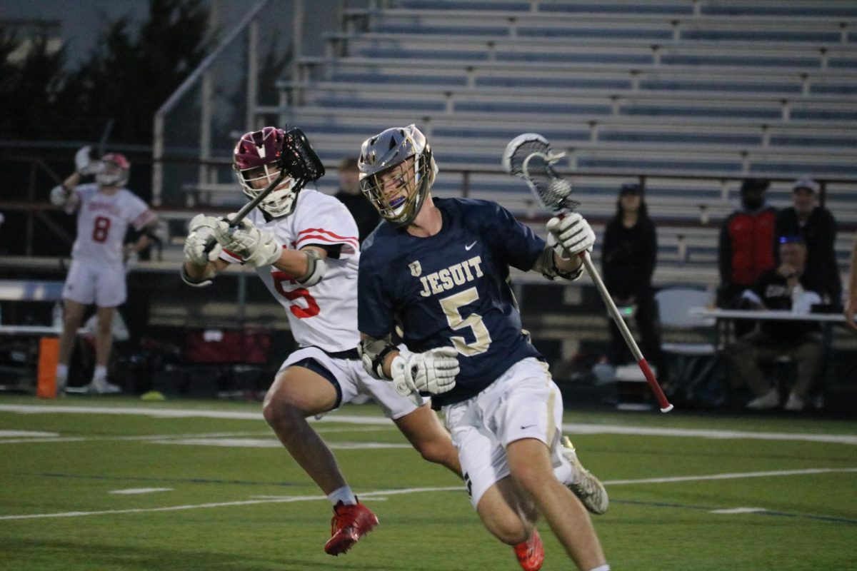 Coppell senior defense Nate Sullivan trails Dallas Jesuit junior forward Caleb Caldwell on March 22 at Lesley Field. The Rangers defeated the Cowboys, 23-1.