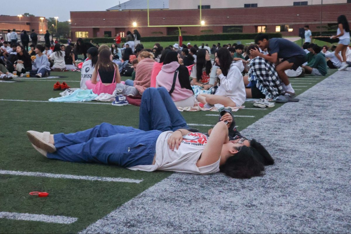 Coppell seniors Carleigh Fezzey and Aditi Govil lie on the turf, watching the sunrise together on April 24 at Buddy Echols Field. CHS Student Council hosted its annual senior sunrise and provided breakfast for Coppell seniors. 