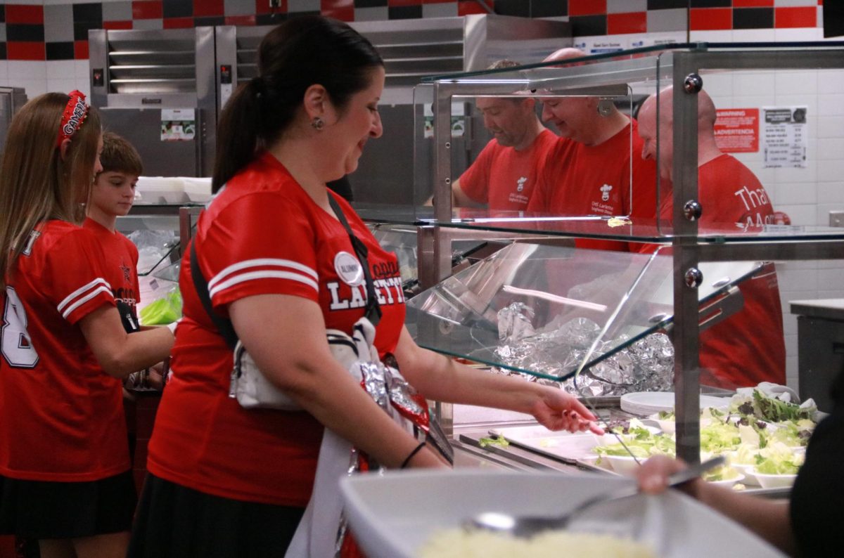 Attendees of the annual Lariette Spaghetti Dinner receive their food from parent volunteers in the Coppell High School Commons on Friday. The Lariettes hosted their 35th annual Spaghetti dinner to kick off the high school football season and fundraise for their program. 