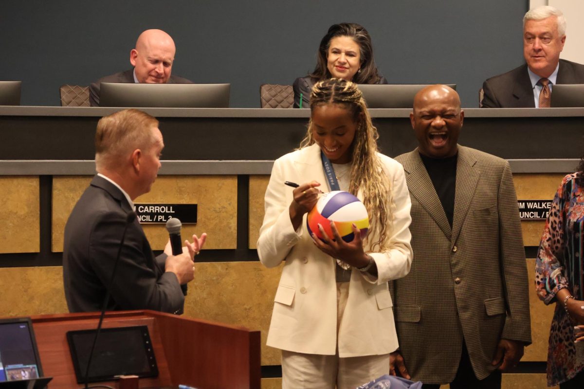 Coppell High School 2013 alumna and Olympic volleyball medalist Chiaka Ogbogu signs a volleyball to display in Coppell City Hall with Mayor Wes Mays on Tuesday. At the meeting, Sept. 24 was declared as Chiaka Ogbogu Day in honor of Ogbogu’s impact on the community.