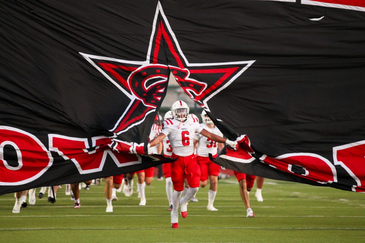 Coppell senior running back O’Marion Mbakwe breaks through the banner prior to  kickoff against  Waxahachie at Stuart B. Lumpkins Stadium on Sept. 6. Mbakwe plays a significant role in the Cowboys’ offense, showcasing his work ethic on and off the field.