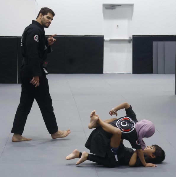 Coach Matheus Galvo instructs Laila Darwish as she practices a grappling technique with Idrees Usmani during a Jiu-Jitsu class at Sixth Sense Martial Arts on Oct. 7. Sixth Sense offers martial arts training for all ages, emphasizing self-defense and anti-bullying. 