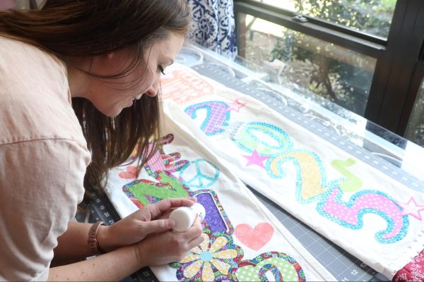 Jewels N Cotton owner Jennifer Ham finishes off a senior overall by outlining letters with puffy paint. Jewels N Cotton is a small Coppell business selling custom spirit wear. 