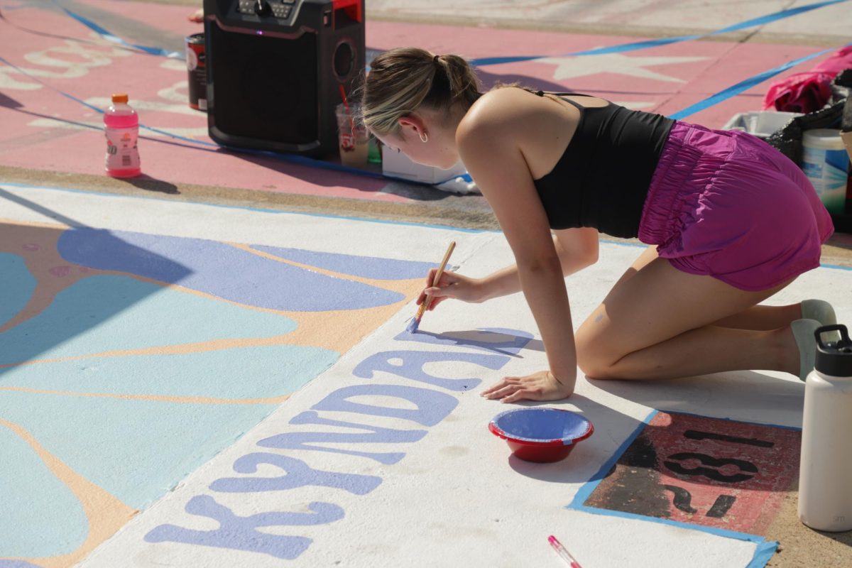 Coppell High School senior Kyndal Ritch paints her name onto her parking spot on Sept. 21 in the student parking lot. Seniors came out on Sept. 20-22 to paint their parking spots, an annual CHS tradition carried on by senior classes.