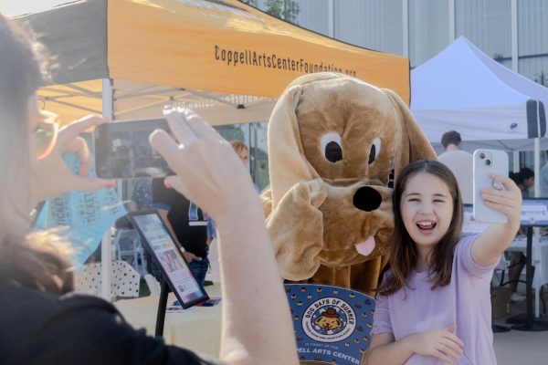 Coppell Arts Center Foundation president Leigh Walker takes a photo of attendee Sophia Bowman with the Dog Days of Summer mascot. On Oct. 5, Coppell Arts Center hosted its annual dog fashion show and adoption event at The Grove. Photo by Caitlyn Concepcion 
