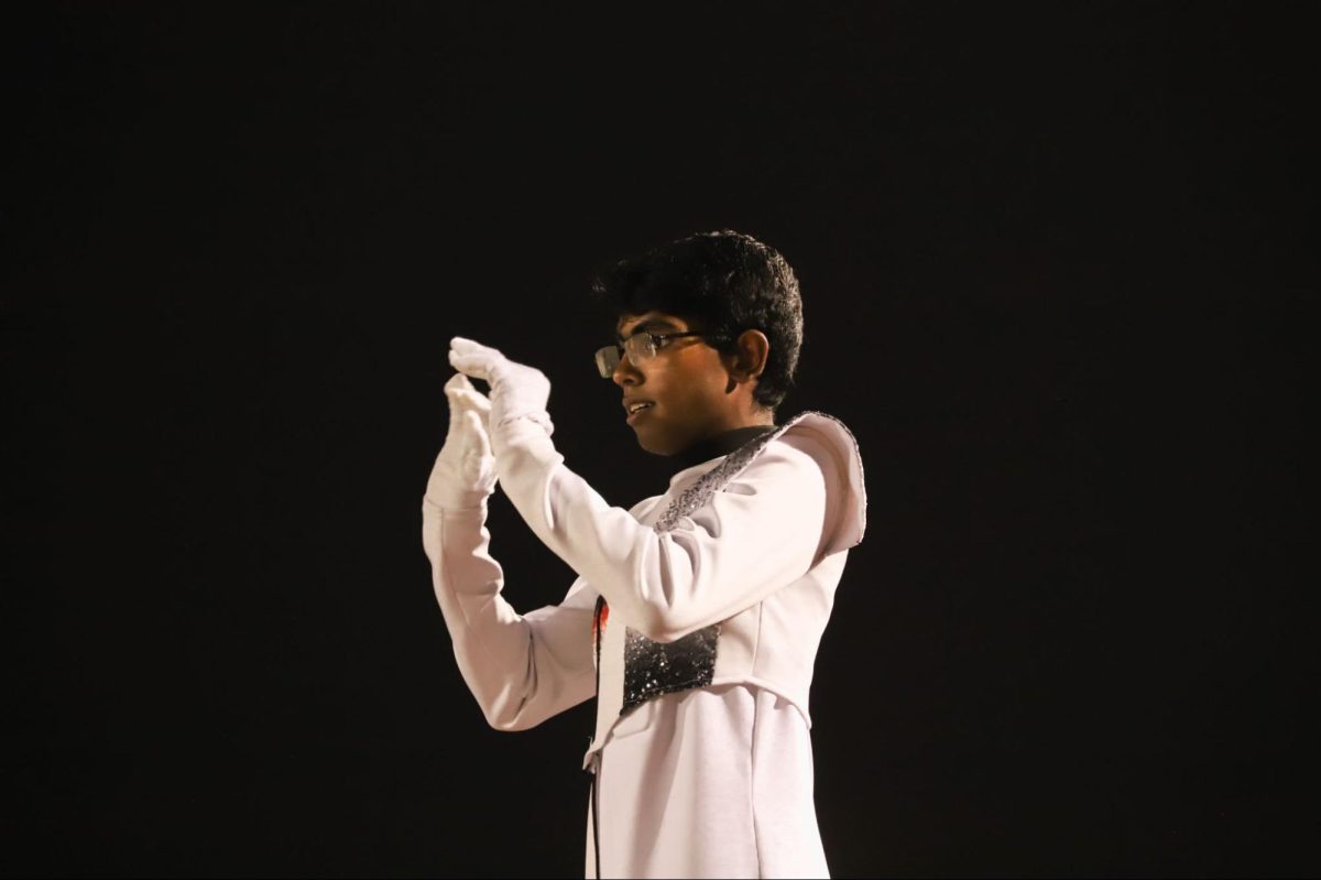 Coppell High School senior Siddharth Bellam conducts the Coppell Marching Band during the halftime performance of its 2024 show, “OrganIC,” at the football game against Flower Mound Marcus on Nov. 7. Bellam serves as the head drum major of the Coppell Marching Band, leading the program through commitment and dedication. 