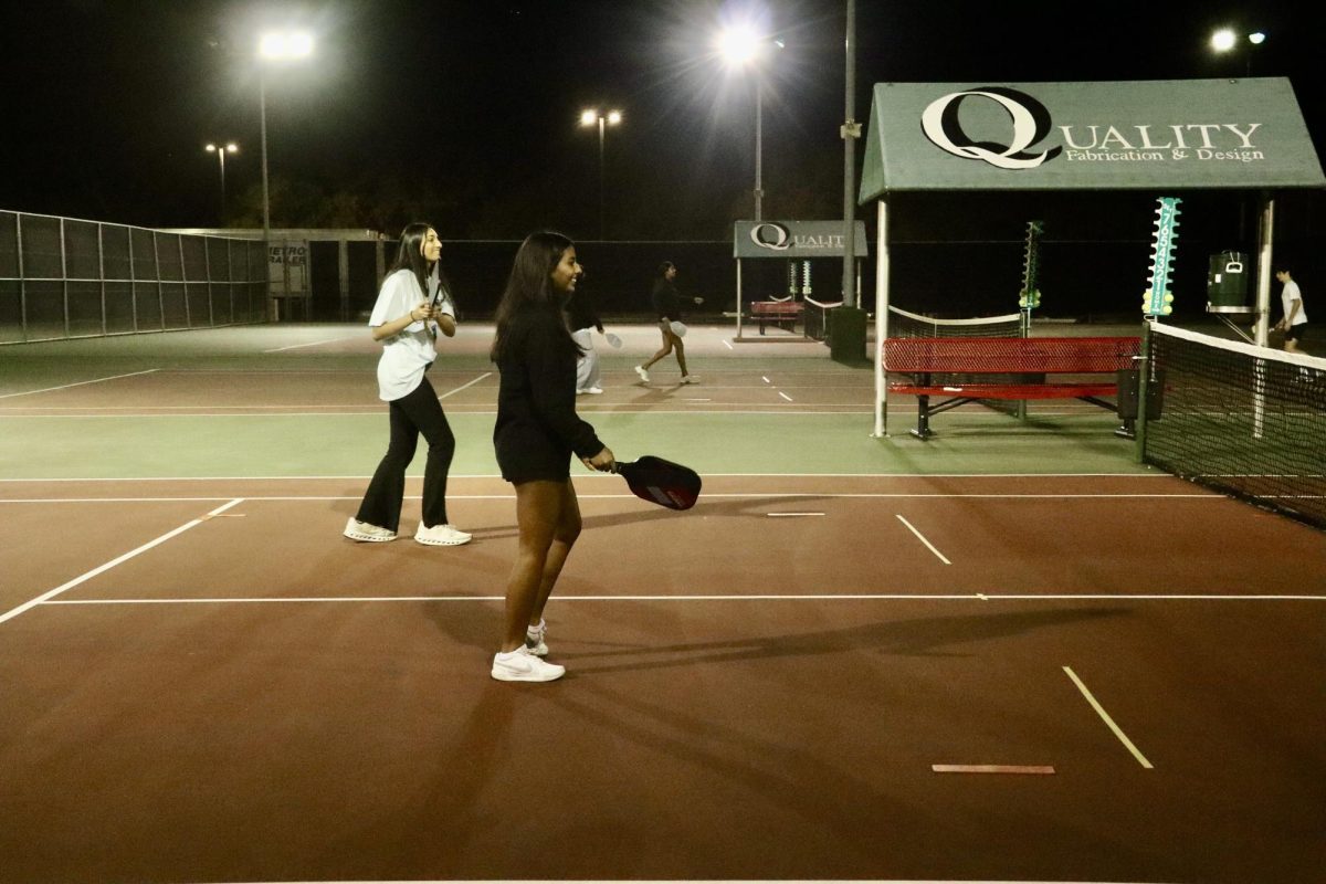 Coppell High School seniors Aishwarya Anandkumar and Divya Sharma play pickleball at the tournament hosted by Think Kids Yuva at the CHS tennis courts on Nov. 21. Pickleball has helped strengthen bonds among the Coppell community. 