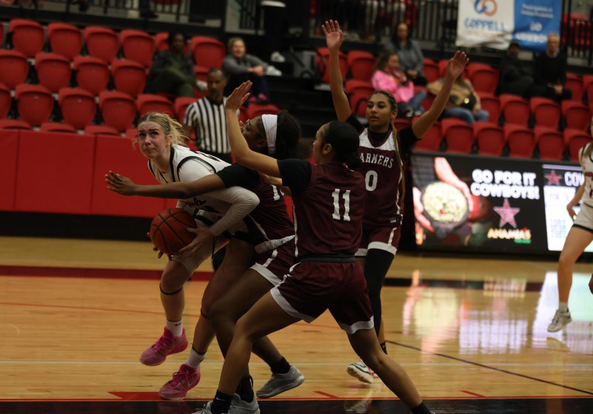 Coppell junior forward Adriana Reijnen eyes the basket while being defended by Lewisville freshman point guard Siryah Foreman and senior shooting guard Keelayna McClendon at the CHS Arena on Friday. The Cowgirls defeated the Farmers, 52-43. Photo by Raima Awan.