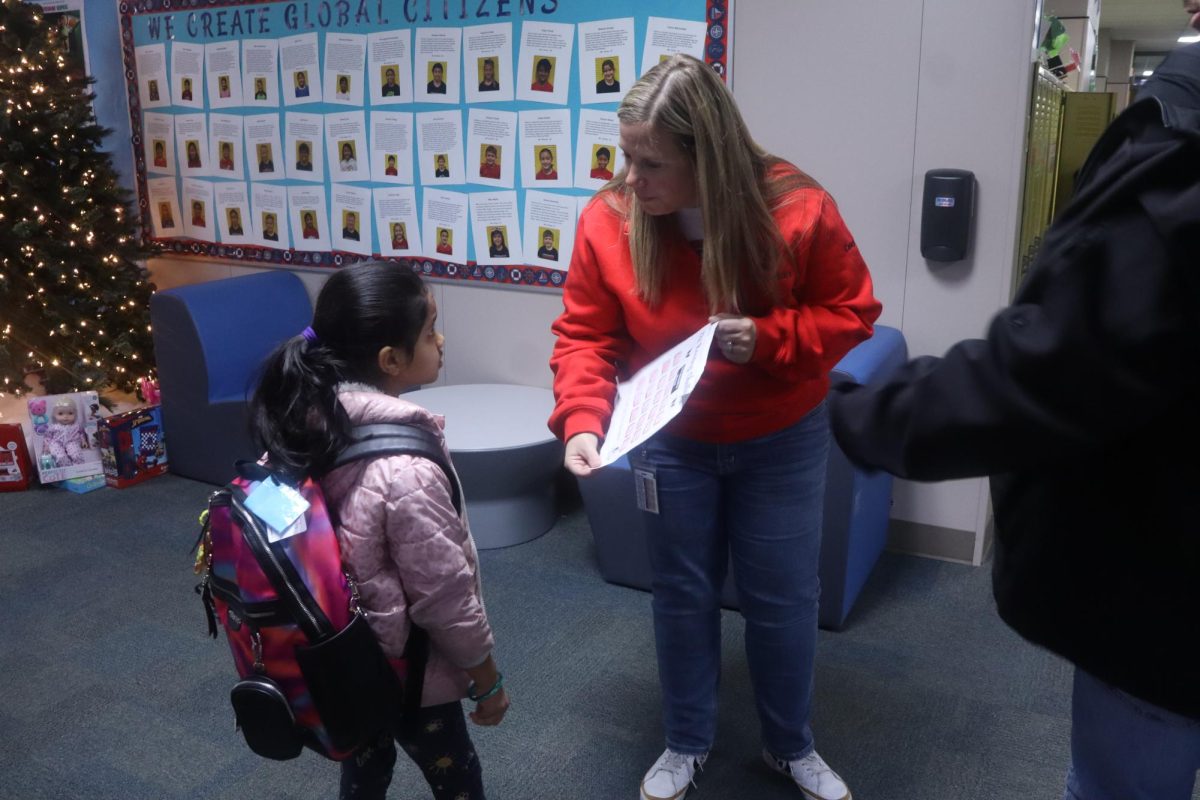 Pinkerton Elementary School Principal Amanda Sweeney helps 1st grader Srihitha Thummalapally understand the Pinkerton Christmas paper. Sweeney will take over as principal of Wilson Elementary School for the 2025-26 academic year.