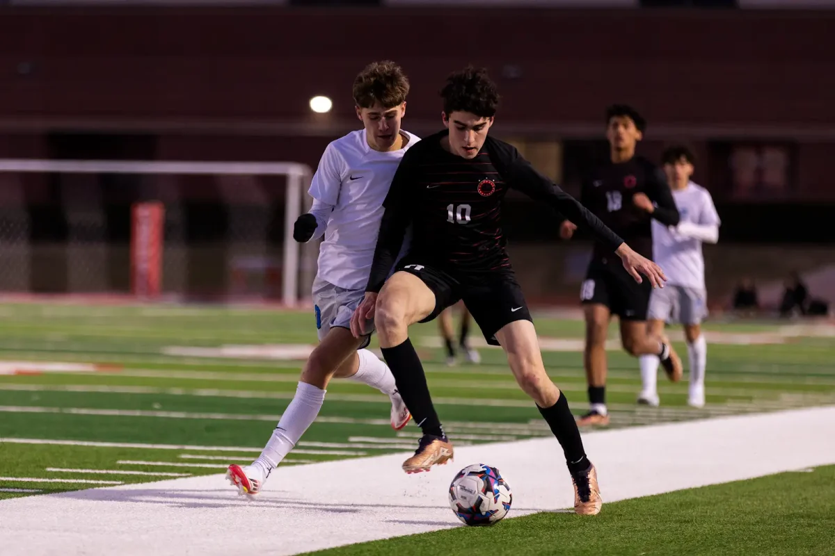 Coppell senior midfielder Caden Naef and Hebron senior defender Mason Hatley fight for possession at Buddy Echols Field on Tuesday. The Cowboys and Hawks ended in a 0-0 draw. Photo by Kayla Nguyen.
