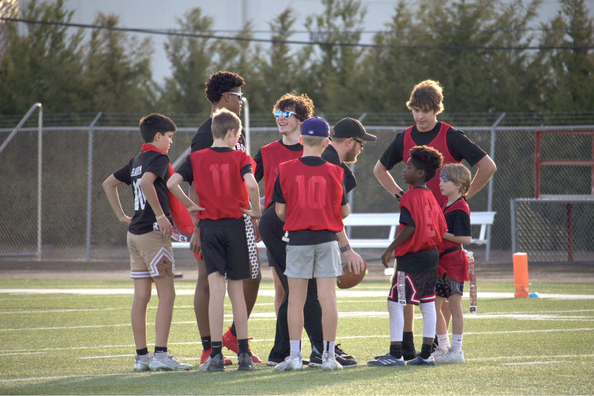 Coppell High School Football and Coppell Youth Football Association players huddle during the Red vs. Black game on Feb. 3 at Lesley Field. CYFA hosted its second annual community game and punt, pass, kick tournament with Coppell High School football.
