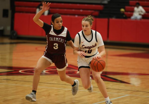 Coppell senior guard Landry Sherrer runs through the defense of Lewisville senior point guard Milan Norman at CHS Arena on Friday. The Cowgirls defeated the Farmers, 52-43. Photo by Raima Awan.