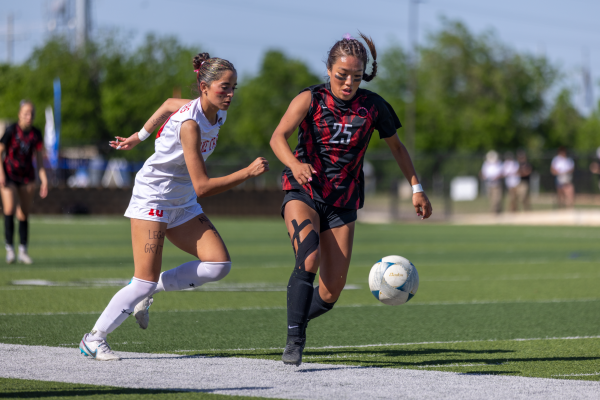 Coppell senior midfielder Summer Chen drives past Lake Travis junior forward Amelia Clark at Birkelbach Field in Georgetown on April 12. The Cowgirls defeated Lake Travis, 6-2, to win the Class 6A Division I state championship for the first time in 10 years. Photo by Kayla Nguyen. 