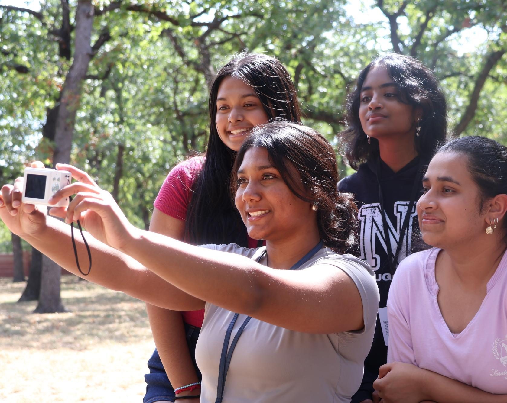 Coppell High School sophomores Akshata Ghosh and Varshini Avula and juniors Vidya Praveen and Aashi Panchal take a group selfie with a digital camera. With new state laws implementing phone ban policies, students utilize digital cameras to make memories without using phones.