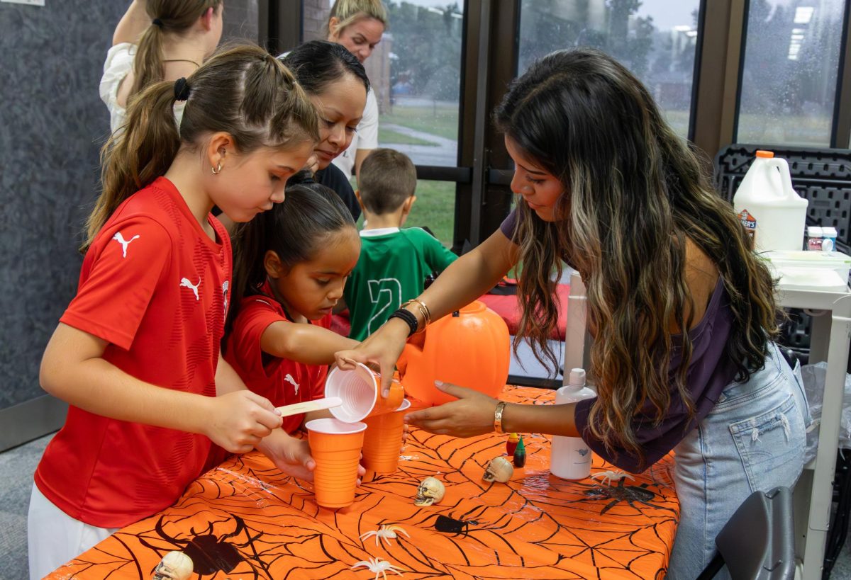 New Tech High @ Coppell senior Kiara Sanchez assists participants Cooper Whitlow and Diana Lopez to make slime on Saturday at New Tech High @ Coppell. New Tech hosted its annual Fall Festival with games, activities and food to celebrate Halloween festivities. Photo by Rachel Chio