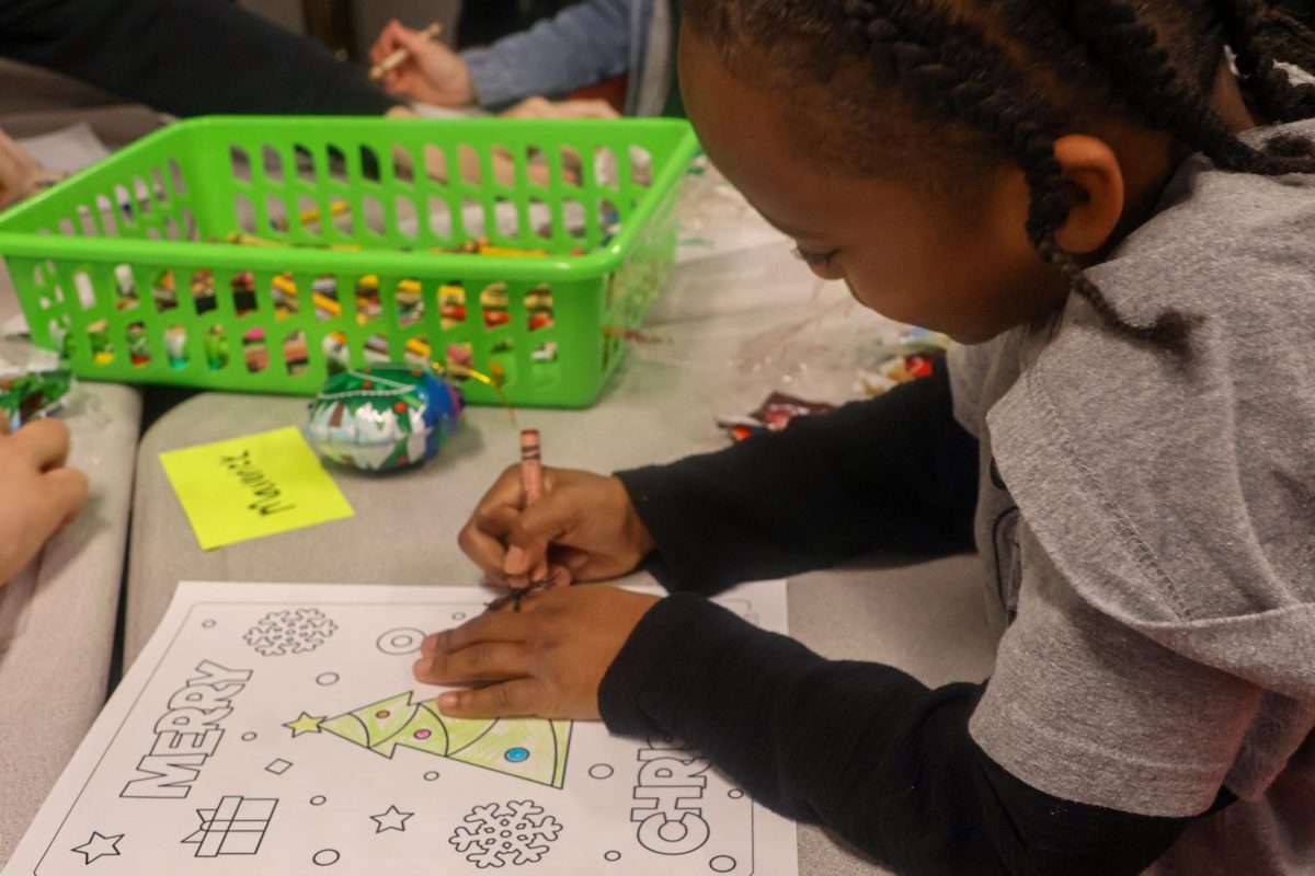 Cottonwood Creek Elementary first grader Maverick Williams colors in a Christmas tree coloring page on Dec. 1 in Coppell High School English IV Courtney Ferrell's class. Letters to Santa is an annual field trip for CCE students to bond with CHS seniors during the Christmas season. 