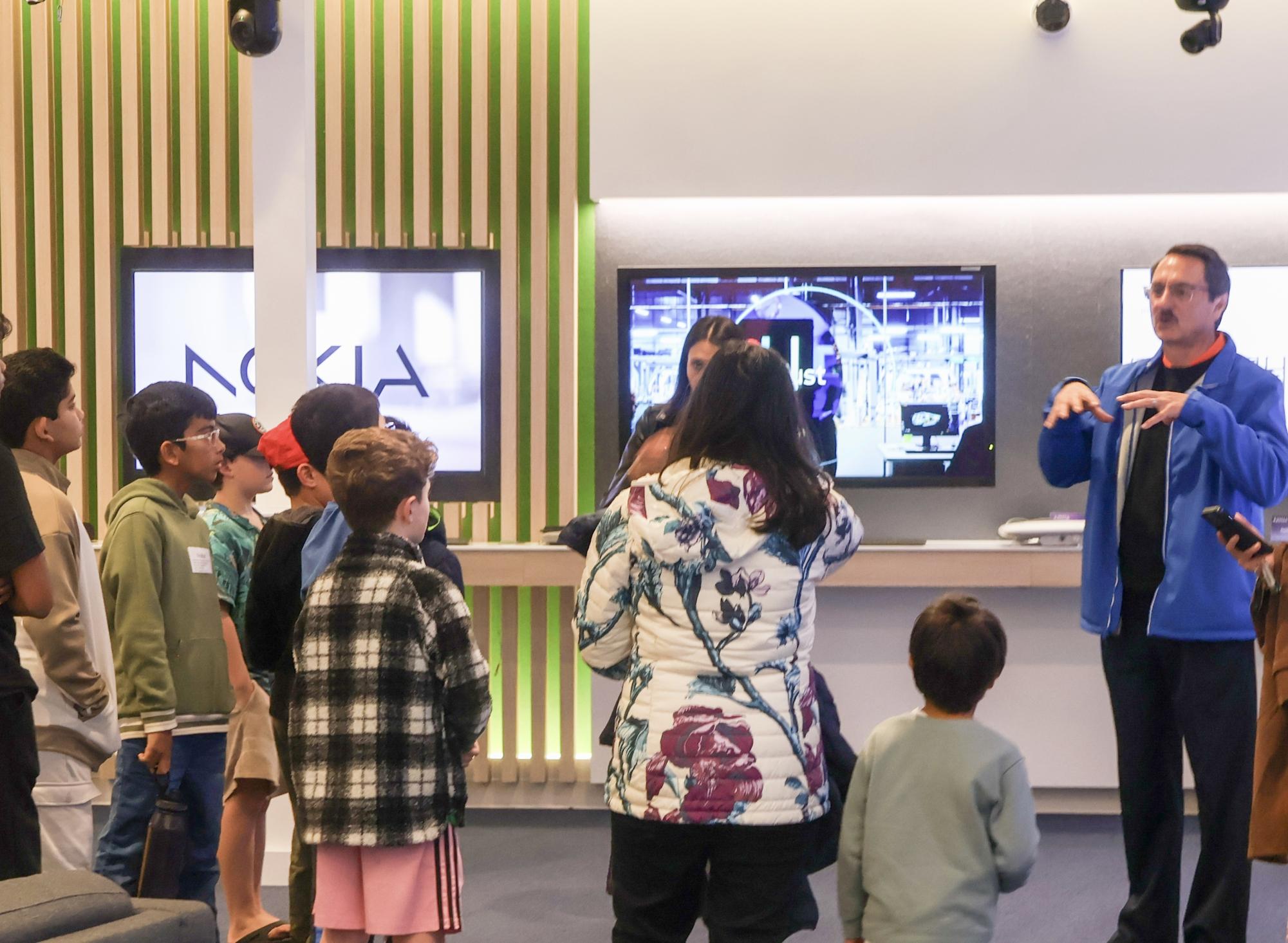 Nokia staff member Raymond Coral leads SAGE participants touring Nokia’s technology displays on Dec. 16 at the Nokia building in Cypress Waters. SAGE collaborated with Nokia for an artificial intelligence seminar and activity tour.