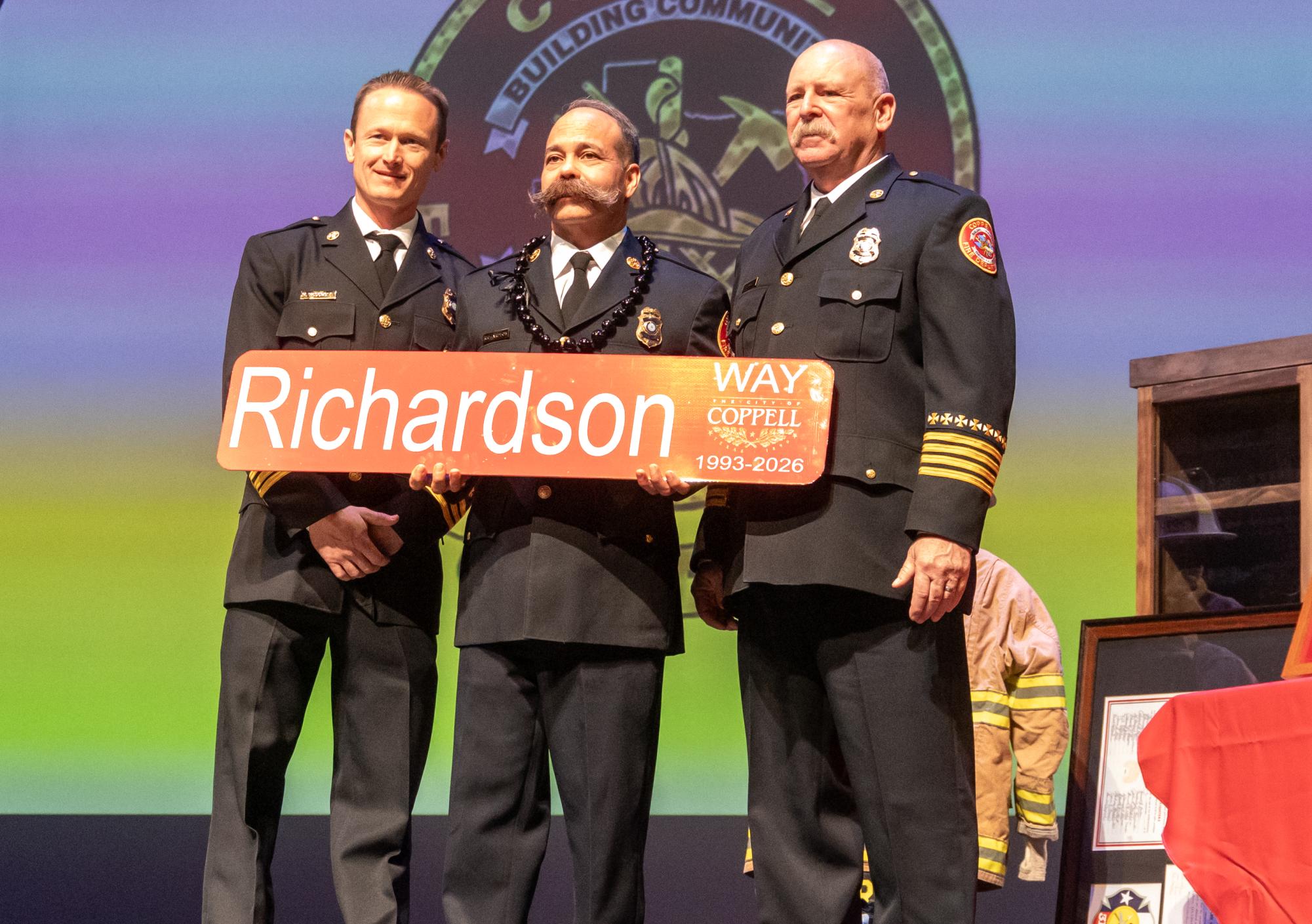 Coppell Fire Department Chief Kevin Richardson (center) receives a street sign at his retirement ceremony at The Coppell Arts Center on Tuesday. After serving as the Coppell Fire Department’s Chief for two decades, Richardson’s last day is Friday.