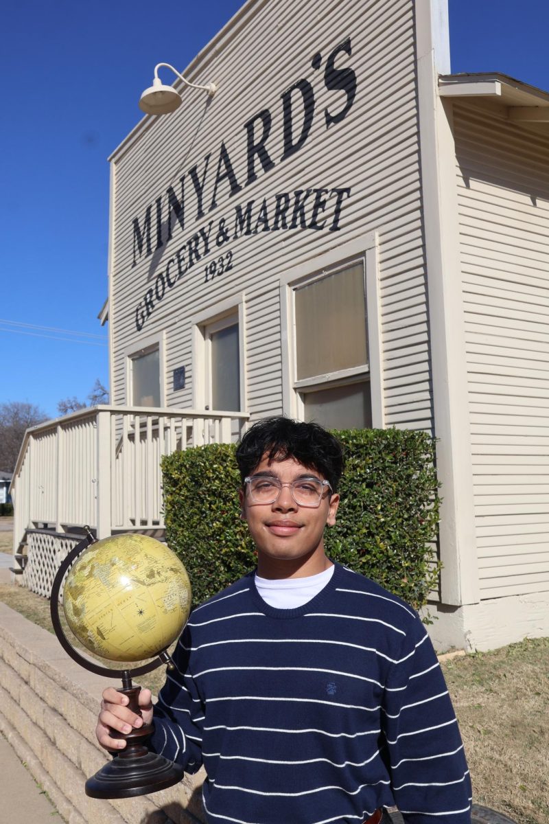 The Sidekick editor-in-chief Yug Talukdar holds a globe in front of Minyard’s Grocery and Market. For Talukdar, history influences his activities and perspective on the world around him. 