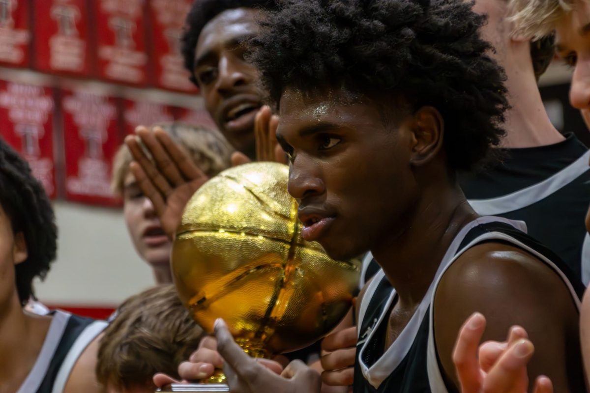 Coppell junior guard Robert Watson lll  celebrate with the area championship trophy after defeating Arlington Martin on Friday at Euless Trinity. The Cowboys defeated the Warriors, 63-60, in the Class 6A area playoffs. Photo by Reece Murry