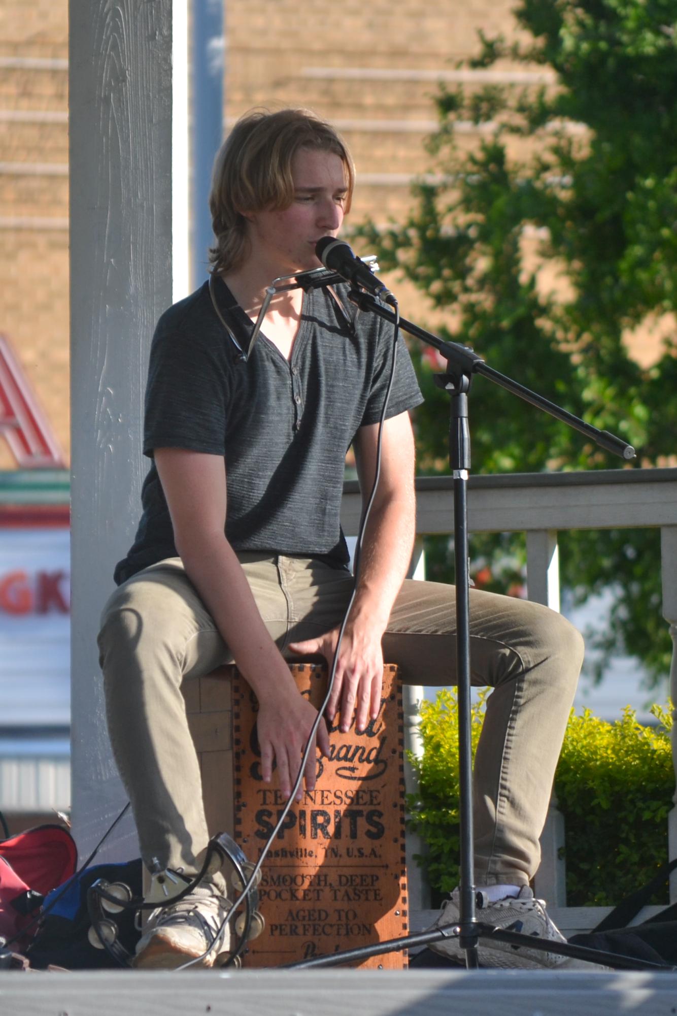 Baylor sophomore Gedeon Bring sings backup vocals while playing a cajon with his hands and a tambourine with his foot for the Colton Hamilton Band at Sounds on the Square in Carrollton on April 11, 2025. Bring enjoys learning about local history and is a professional drummer for the Colton Hamilton band. Photo courtesy Alyssa Gray.