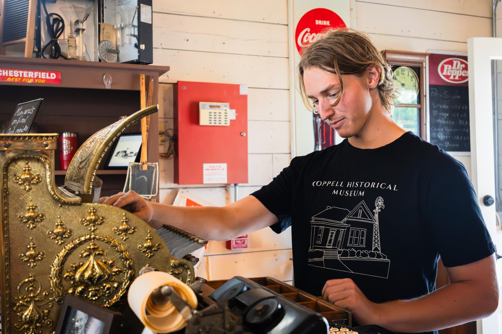 Baylor University sophomore and author Gedeon Bring demonstrates a transaction on an antique cash register at Minyard’s Store Museum and Gift Shop. Bring enjoys learning about local history and is a professional drummer for the Colton Hamilton band.