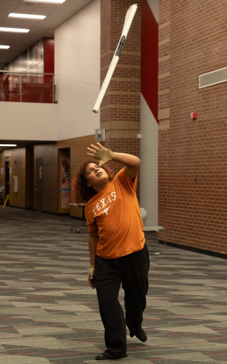 Coppell High School senior Vi Moya practices tossing rifles in the main hallway. Moya strives to continue color guard during college years. 